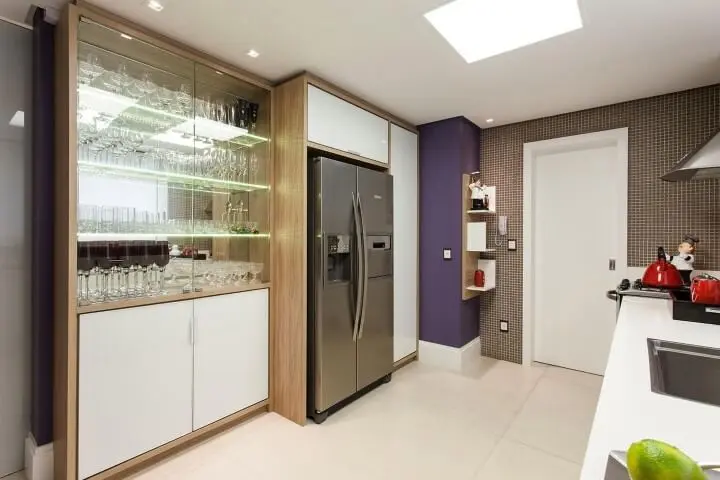 Cozinha planejada com cristaleira moderna com portas de vidro e iluminação nas prateleiras Projeto de Juliana Pippi