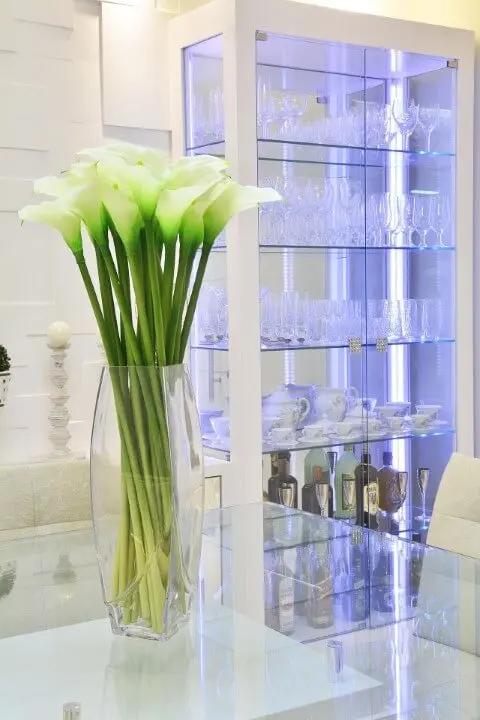 Cristaleira moderna de vidro com estrutura branca em sala com decoração clara Projeto de Graça Brenner