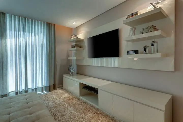 Sala de TV com parede cor palha e móveis planejados em tom claro de bege Foto de Isabella Magalhães Arquitetura & Interiores