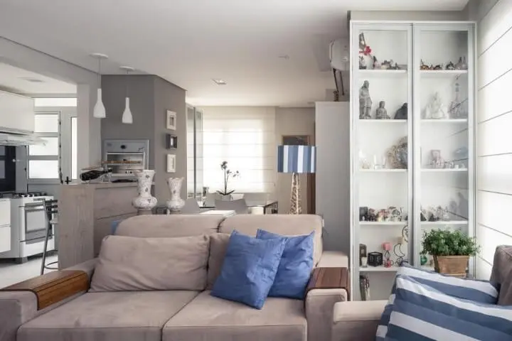 Sala de estar com cristaleira moderna branca com objetos de decoração dentro Projeto de Braccini Lima