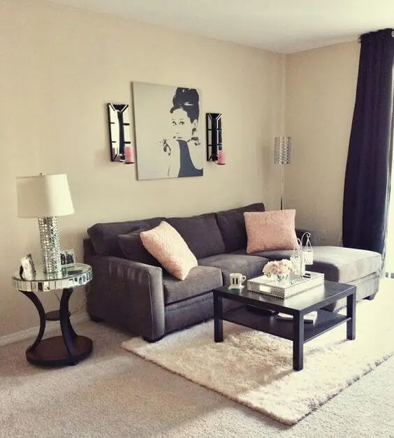 Sala de estar com parede cor palha, sofá cinza e toques cor de rosa Foto de Viver em Casa