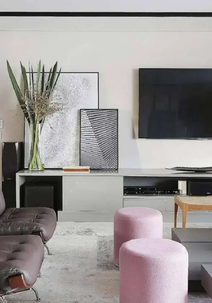 objetos de decoração para sala moderna com puffs cor de rosa claro e quadros apoiados na rack Foto Dcore você