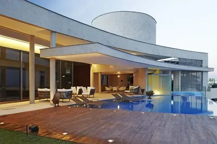 Casa moderna com piscina com deck de madeira e espreguiçadeiras na parte rasa Projeto de Angela Pinho