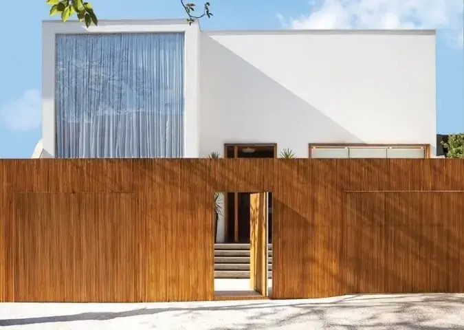 Casa moderna com portão de madeira e porta do mesmo material Projeto de Francisco Calio