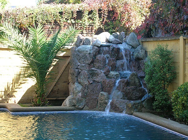 Cascata para piscina com pedras e jardim