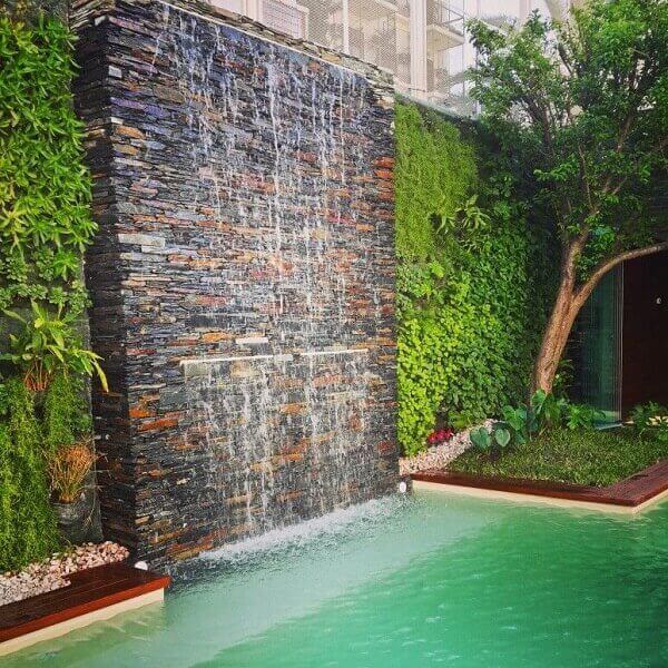 Cascata para piscina embutida em parede de pedras