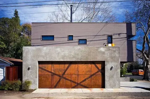 O portão de madeira se conecta perfeitamente com a fachada de concreto da casa