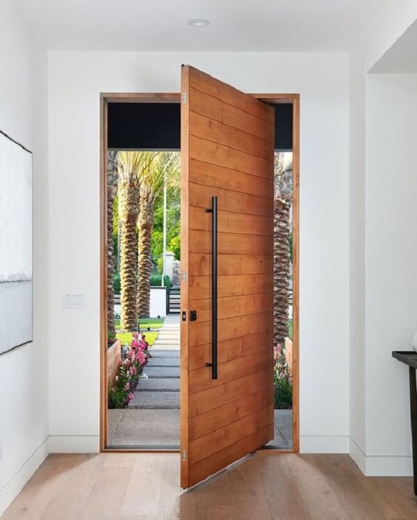 Porta pivotante de madeira traz charme para a fachada da casa