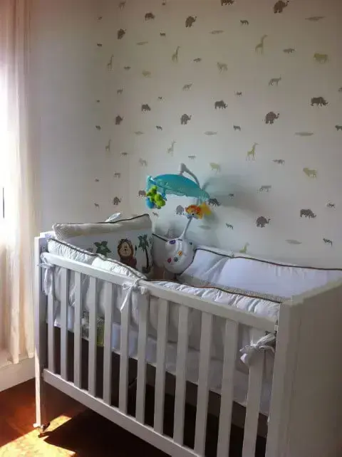 Quarto de bebê menino com berço branco de madeira e papel de parede com animais Projeto de Jessica Nogueira