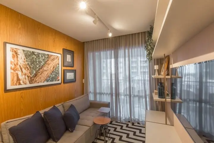 Sala de TV com móveis de madeira e painel na parede Projeto de Emerson Vasconcelos