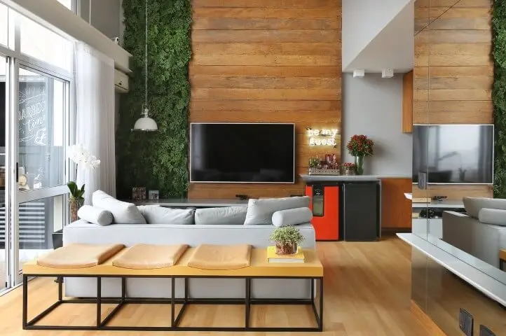 Sala de TV com móveis de madeira painel rústico na parede alta Projeto de Estudio AE