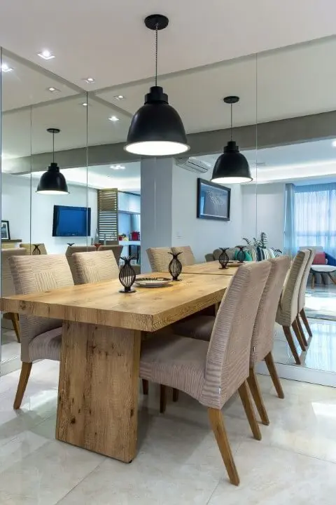 Sala de jantar espelhada com móveis de madeira mesa e pés de cadeira Projeto de Milla Holtz