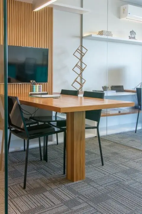 Sala de reunião com móveis de madeira mesa embutida no painel Projeto de Danyela Correa