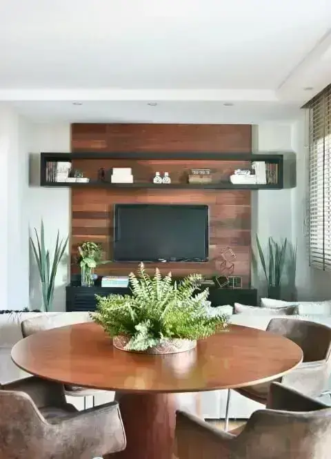 Sala integrada com móveis de madeira mesa redonda e painel de TV Projeto de Tetriz Arquitetura