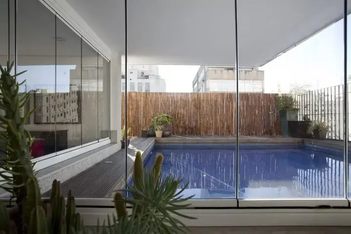 Terraço com piscina com deck e cerca de bambu em volta Projeto de AMC Arquitetura