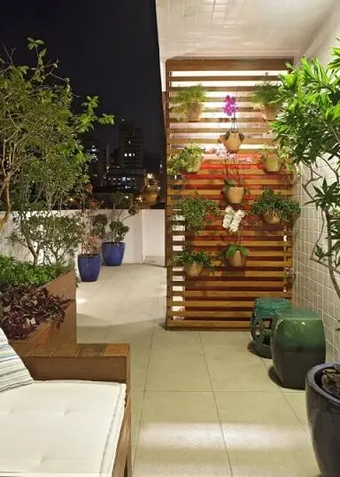 Varanda de apartamento com móveis de madeira painel para vasos de flores Projeto de Amis Arquitetura