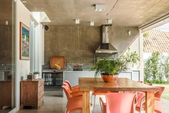 Varanda gourmet com móveis de madeira mesa com cadeiras laranja Projeto de AMC Arquitetura