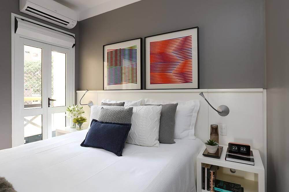 quarto de casal moderno decorado em tons de cinza e branco com quadros sobre a cabeceira Foto Now Arquitetura