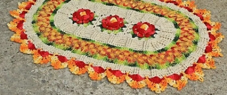 tapete crochê oval com flor vermelha e detalhes em amarelo e laranja Foto Artes da Desi
