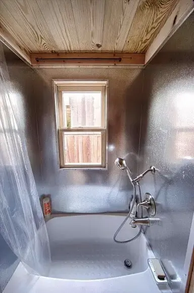 Banheira pequena em canto com paredes prateadas e cortina de plástico Foto de Arch DSGN