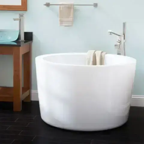 Banheira pequena redonda branca em banheiro com o chão preto Foto de Mukpin