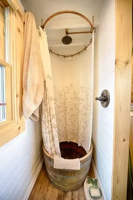 Banheira pequena redonda de madeira com chuveiro no teto e cortina de plástico com estampa floral Foto de White House 51