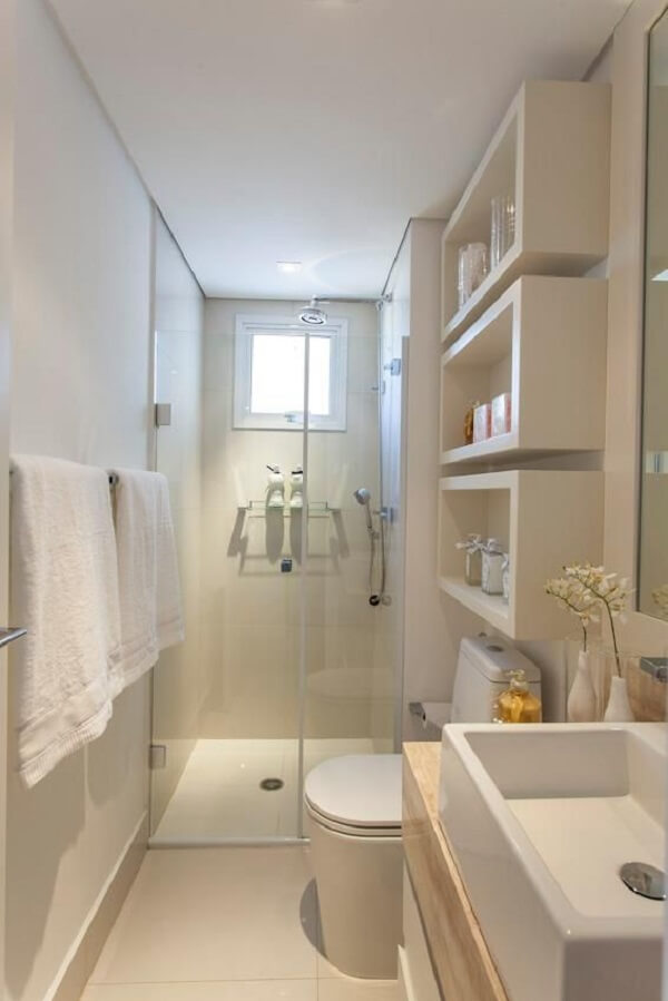 Banheiro pequeno decorado com prateleiras na cor branca