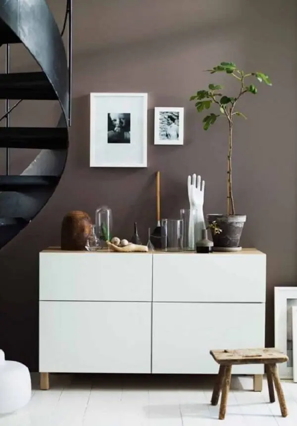 Os móveis em tom branco quebram a seriedade da parede marrom. Fonte: Pinterest