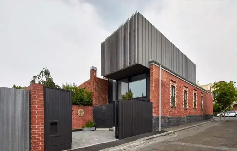 Portão de ferro preta em casa grande com muro de tijolinhos Foto de Home DSGN