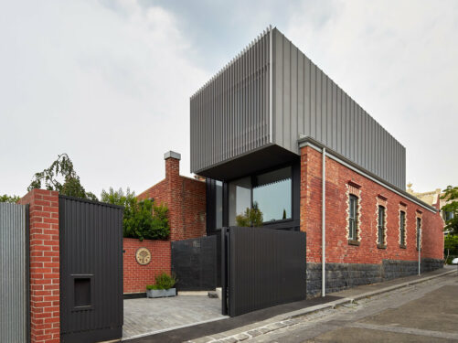 Portão de ferro preto em casa grande com muro de tijolinhos