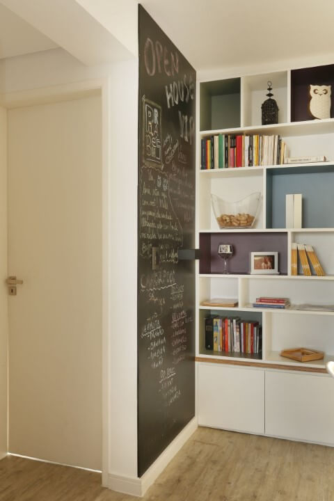 Sala de estar compacta com cadeiras coloridas e painel chalkboard em parte da parede Projeto de SP Estudio1