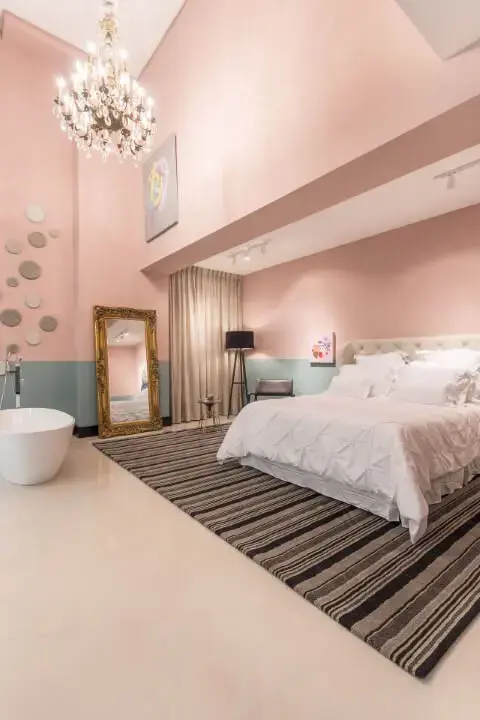 Suíte ampla com paredes rosa e azul com banheira pequena branca Projeto de Jean Felix