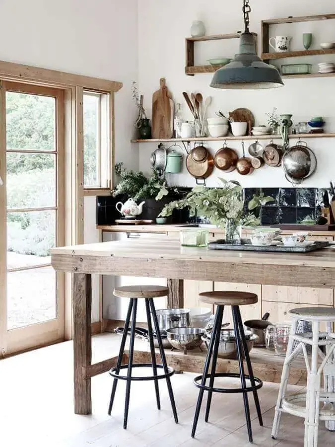 cozinha rústica decorada com mesa de madeira e várias panelas penduradas Foto The Cottage Market