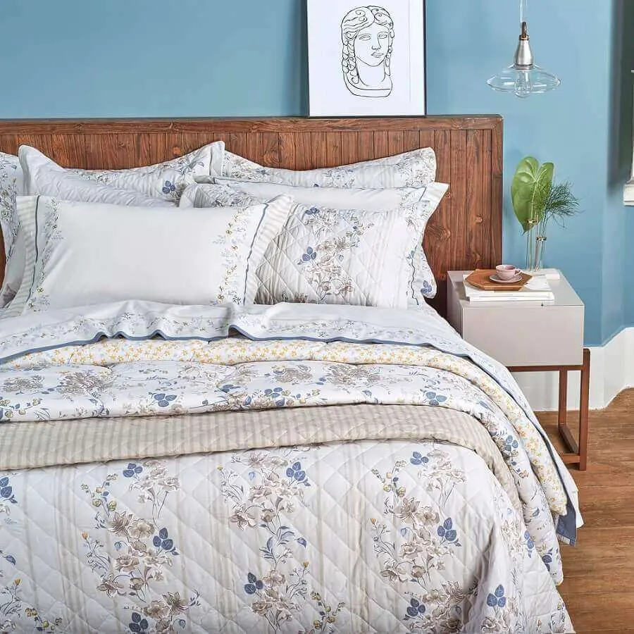 decoração de cama com cabeceira de madeira com muitos travesseiros e enxoval bonito