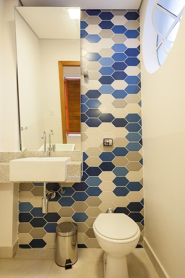 Banheiro decorado com revestimento hexagonal em tons de azul, cinza e branco
