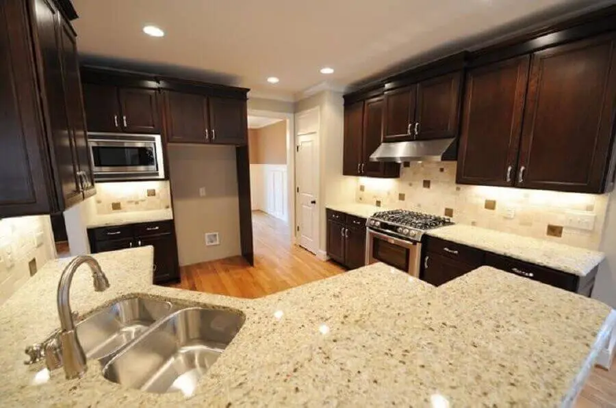 decoração cozinha planejada com armário de madeira escura e granito branco Dallas Foto Istock