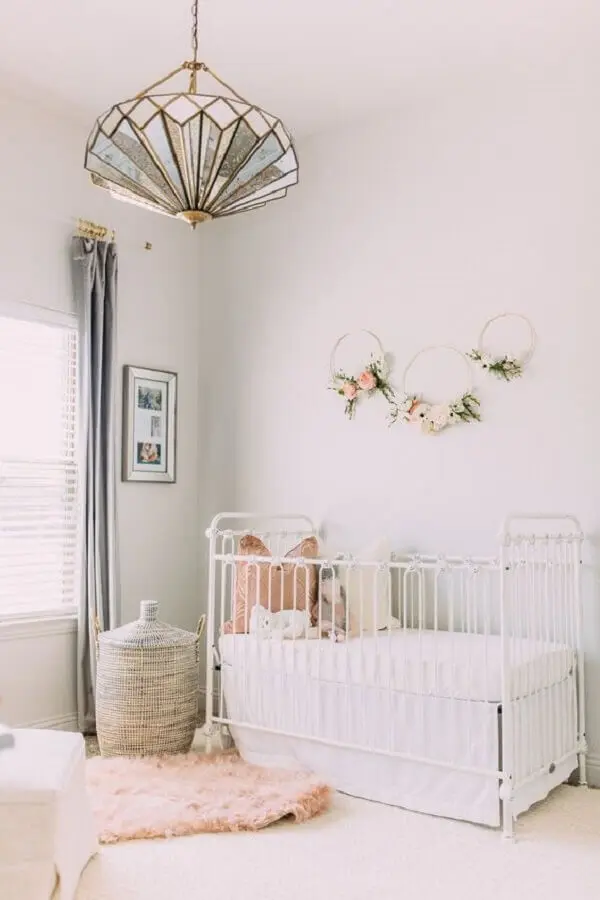 lustre para quarto de bebê feminino decorado com berço branco e argola com arranjos de flores na parede Foto Mabel + Moxie