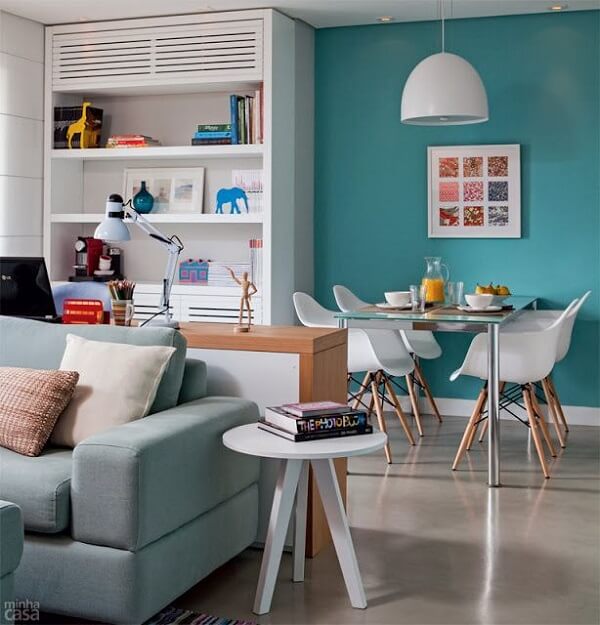 A parede azul turquesa transmite elegância nessa sala de estar pequena