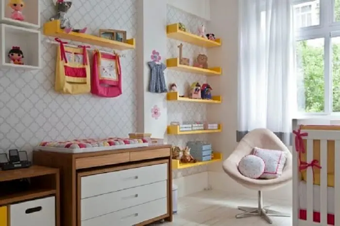 A prateleira para quarto de bebê em tom amarelo traz alegria para a decoração