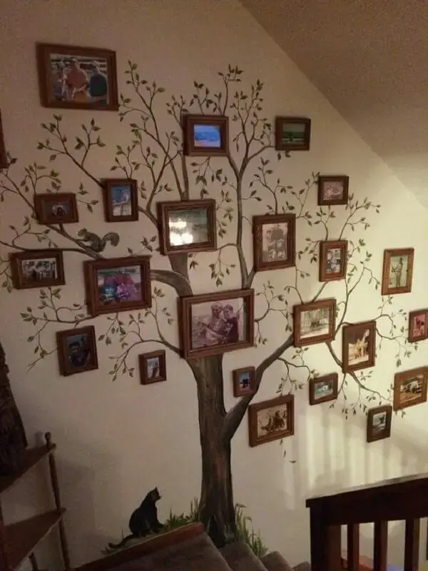 Adesivo de árvore ao pé da escada com quadro de fotos