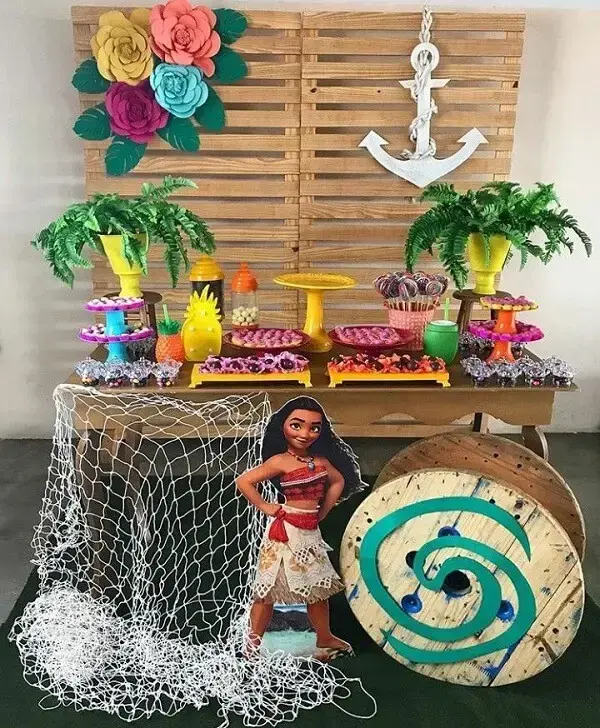 Birthday party with Moana theme has pallet panel and wooden table