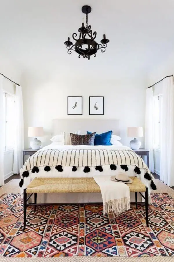 O recamier ao pé da cama que compõem a decoração de quarto simples serve de apoio para acessórios do casa