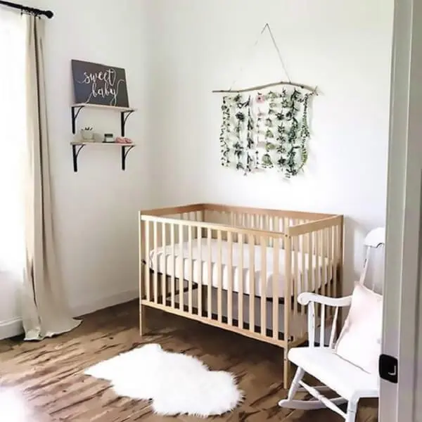 Tapete pequeno e parede com tecido compõem a decoração do quarto de bebê simples