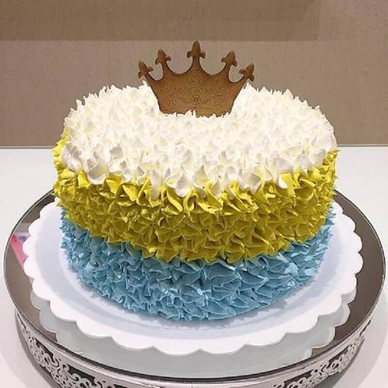 bolos decorados simples com chantilly branco amarelo e azul com pequena coroa no topo Foto Air Freshener