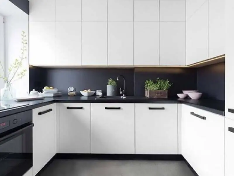 cozinha planejada preta e branca decorada com piso e revestimentos pretos e armários brancos Foto Idea Brasil