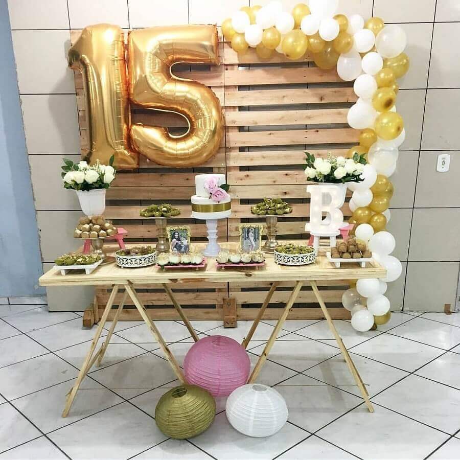 decoração para festa de 15 anos simples com painel de pallets e balões dourados Foto Le’ Art Decor