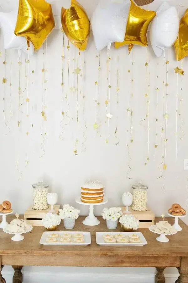 decoração para festa de aniversário branca e dourada com balões em formato de estrela e mesa de madeira Foto Suzanne Carey Photography