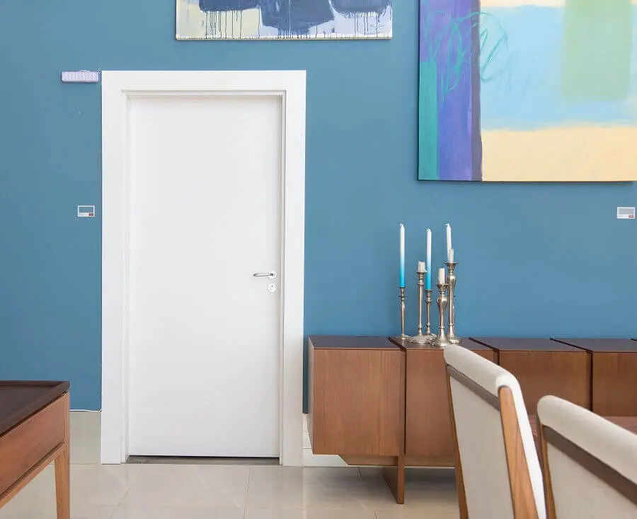 decoração sala de estar com móveis de madeira parede azul e porta branca