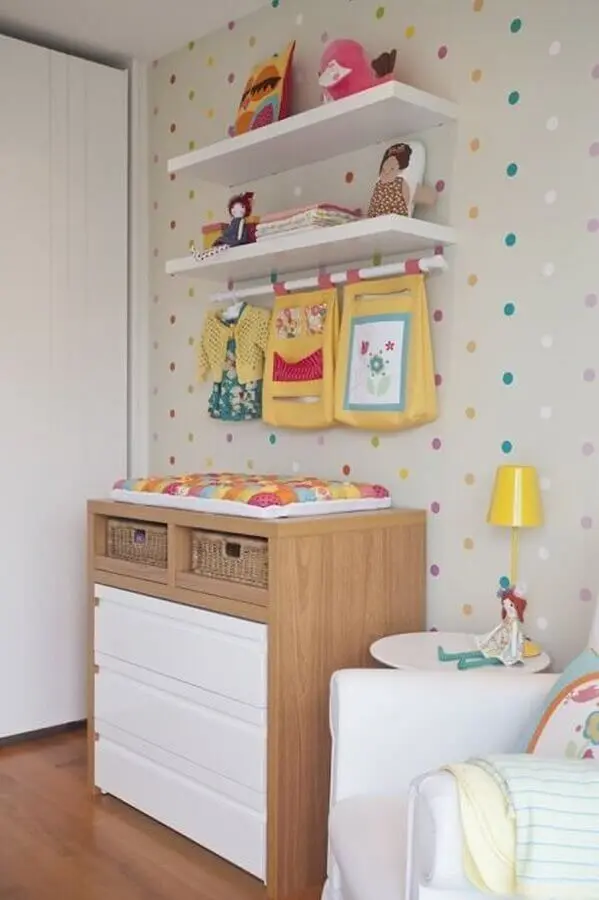 prateleira para quarto de bebê decorado com cômoda de madeira e papel de parede de bolinhas coloridasFoto Vamos Mamães