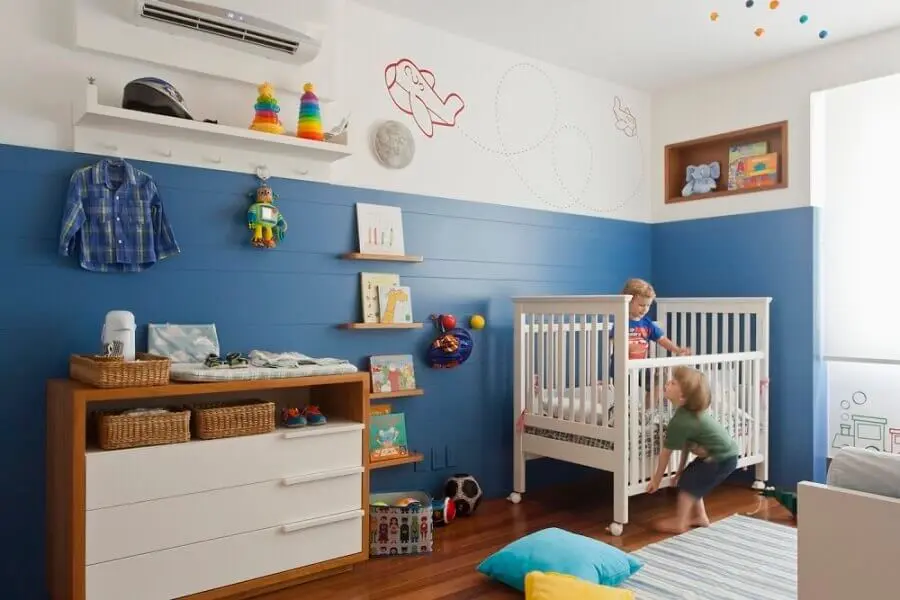 quarto de bebê azul decorado com cômoda de madeira e tapete listrado Foto Natoca Design